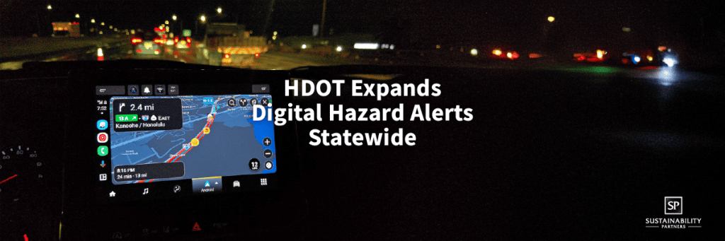 In-vehicle navigation screen displaying a digital hazard alert as a driver approaches a lit roadway work zone at night