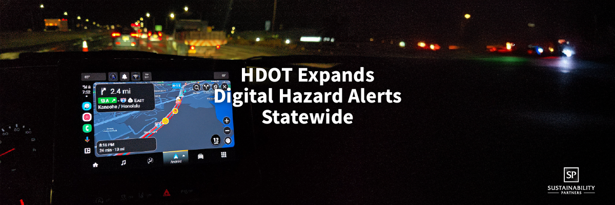 In-vehicle navigation screen displaying a digital hazard alert as a driver approaches a lit roadway work zone at night